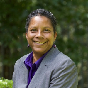 head shot of Archene Turner, Community Minister at Cedar Lane in the courtyard with greenery behind her